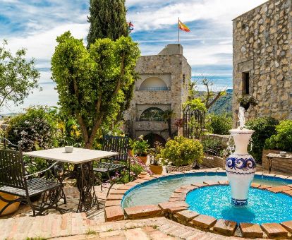 Coquetos exteriores con jardín y mobiliario de este hotel romántico en un castillo.