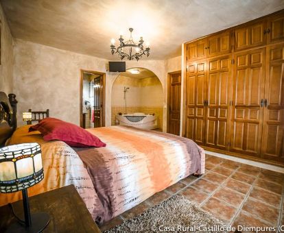 Habitación con bañera de hidromasaje privada junto a la cama en este establecimiento rural.