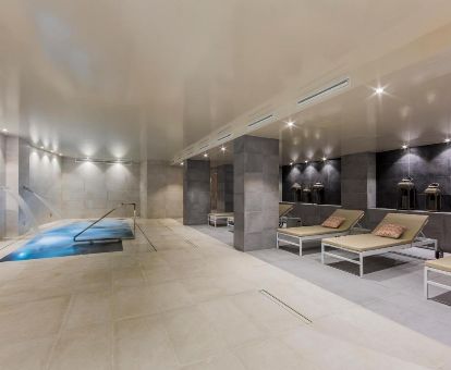 Amplio espacio de bienestar con piscina interior y tumbonas de este moderno hotel ideal para estancias en pareja.