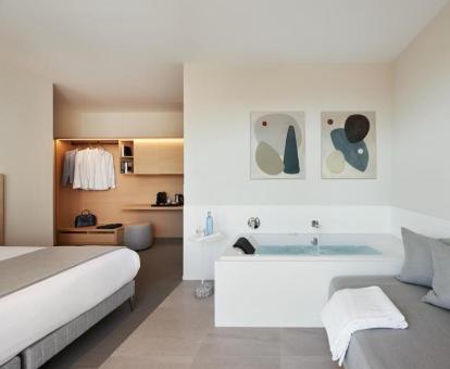Suite junior con bañera de hidromasaje privada junto a la cama y vistas al mar.