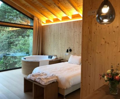 Dormitorio con bañera de hidromasaje privada y vistas a la vegetación que rodea el bungalow deluxe de este complejo turístico, ideal para estancias en pareja.