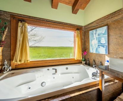 Bañera de hidromasaje privada con vistas de una de las hermosas casas rústicas de este alojamiento en el campo.