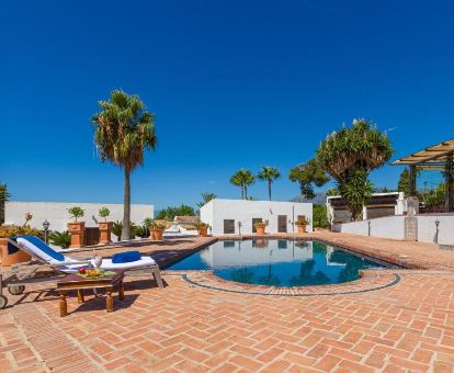 Hermoso cortijo rural con piscina al aire libre y solarium con tumbonas.