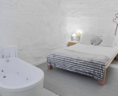 Suite con cama grande y bañera de hidromasaje privada en una cueva ideal para disfrutarla en pareja.