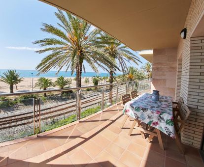 Terraza privada con comedor y vistas al mar de este apartamento independiente en primera línea de playa.