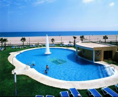 Foto de la piscina con solarium y tumbonas con vistas al mar.