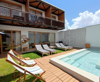 Zona exterior con mobiliario y jardín con piscina de este alojamiento ideal para parejas.