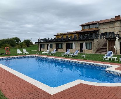 Hotel rural con amplia piscina exterior y tumbonas.