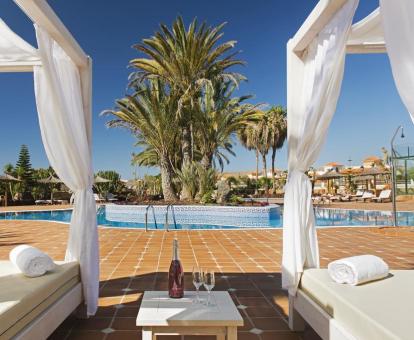 Foto de la piscina con solárium y camas balinesas del hotel.
