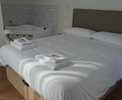 Dormitorio con bañera de hidromasaje privada junto a la cama de uno de los apartamentos del alojamiento.