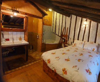 Una de las habitaciones dobles con bañera de hidromasaje privada junto a la cama de este hotel rural.