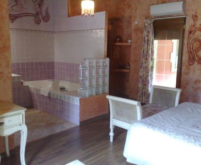Suite con bañera de hidromasaje cerca de la cama de este alojamiento romántico.