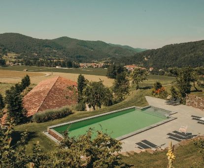 Zona exterior con piscina al aire libre y solarium con vistas a la naturaleza que rodea este hotel.