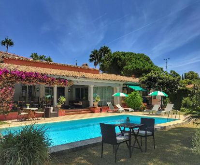 Edificio de este acogedor hotel con zona exterior con mobiliario y piscina al aire libre rodeada de vegetación.