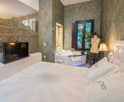 Hermosa suite con bañera de hidromasaje privada junto a la cama en este elegante hotel.