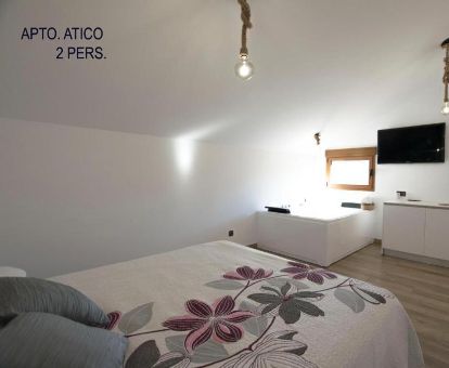 Dormitorio con un gran jacuzzi privado junto a la cama del apartamento ático de este establecimiento ideal para parejas.