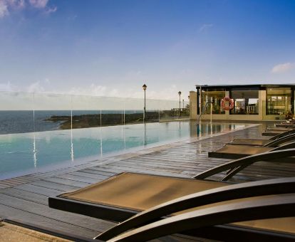 Terraza solarium con vistas al mar y piscina de borde infinito en este hotel solo para adultos.