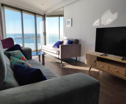 Foto del salón con una amplia cristalera y fabulosas vistas al mar del apartamento.