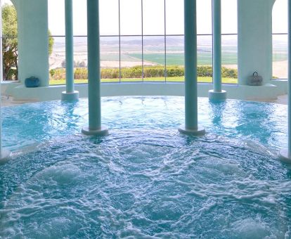 Piscina cubierta con hidroterapia del spa con amplios ventanales y vistas al paisaje que rodea este moderno hotel.