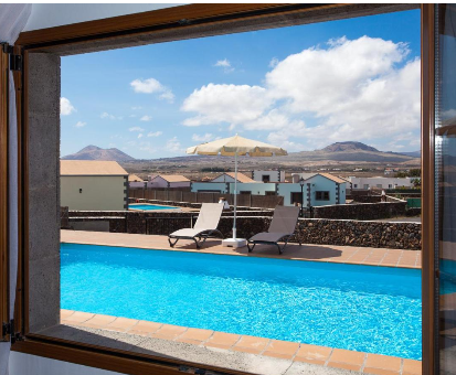 Hermosa piscina al aire libre con vista hacia el pueblo y hacia las montañas aridas de Lajares. Villas Tao Mazo