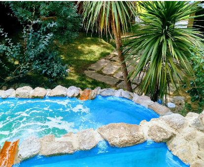 Piscina exterior con cascada situada en el jardín de la casa Almazara de San Pedro en Eljas