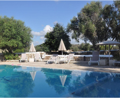 Piscina al aire libre rodeada de grandes arboles en la casa rural Biniati des Pi en Sant Lluis