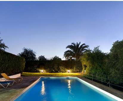 Piscina al interperie cercada con majestuosas plantas y arboles Casa Rural Cuevas del Pino en Villarrubia