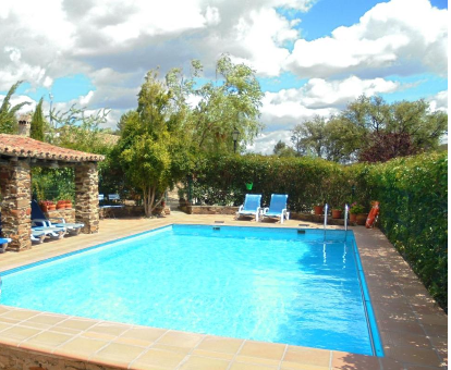 Piscina al aire libre rodeada de hermosas plantas y flores en la casa rural El Jiniebro Valencia de Alcántara