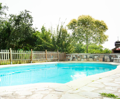 Piscina al intemperie cercada por una basta vegetación verdosa en la Casa Rural Finca Europa Valdunciel 