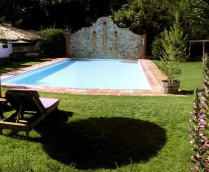 Piscina exterior rectangular localizada en el medio del jardín de la Casa Paraíso del Huéznar en Cazalla de la Sierra