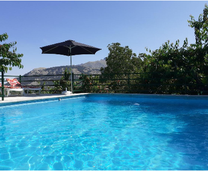 Piscina al aire libre rodeada de hermosas plantas y con vista hacia la montaña. Casa Jurinea en Torres