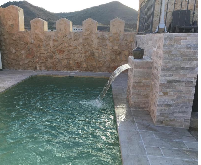 Piscina al aire libre con fuente de agua y vista a las montañas. Casa Rural La Gesta en Jadraque