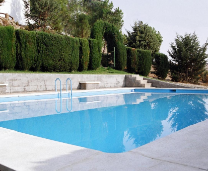 Piscina exterior bordeada de hermosos arboles y plantas de la Casa La Gineta en Ermita Nueva