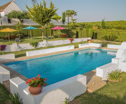 Piscina al aire libre rodeada de bonitas flores y plantas. Hacienda las Marciagas en Benacazón