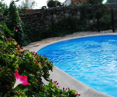 Piscina ovalada exterior cercada por un gran jardín muy pintorezco. Casa Rural Las Navillas en Las Navillas