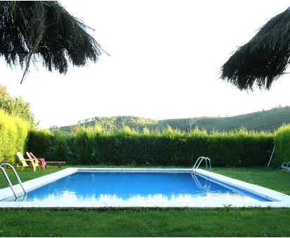 Piscina exterior ubicada en pleno jardín de la casa rural Los Trobos en Villar de Otero