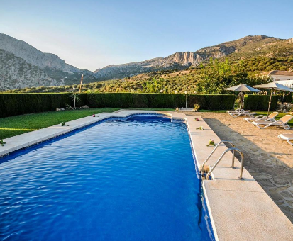 Amplia piscina exterior con fabolusa vista hacia las grandes montañas de Periana. Casa Rural Hotel Marques