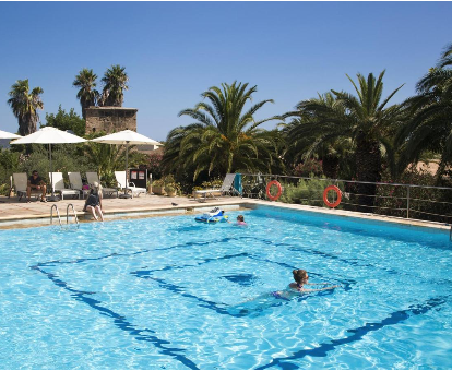 Piscina exterior con fuente de agua y rodeada de hermosas palmeras Finca Hotel Rural Predio Son Serra en Can Picafort