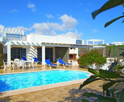 Piscina al aire libre rodeada de plantas y flores. Villas & Spa Sun Grove en Playa Blanca