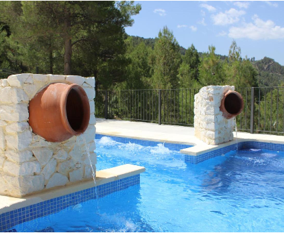 Piscina al aire libre con fuente, rodeada por hermosos pinos. Casa Rural Venta Ticiano El Morrion