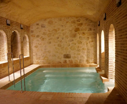 Piscina interior rectangular con vista hacia el jardín de las Casas de Valois en Hita