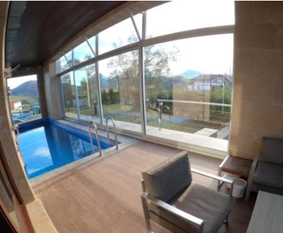 Piscina interior con escalera y vista hacia la naturaleza de Zumaia Villa Montaña Zumaia