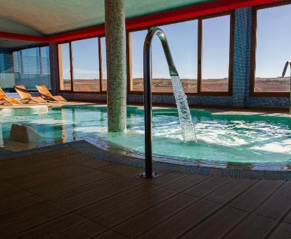 Piscina cubierta con chorros de hidroterapia y vistas del centro de bienestar del hotel.