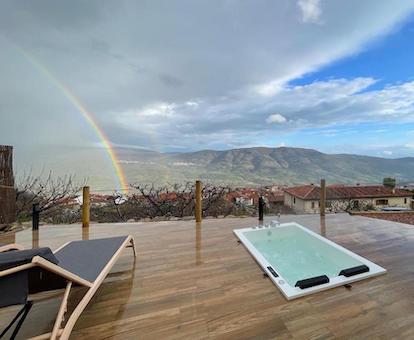 Jacuzzi a ras de suelo en una terraza de madera con increibles vistas junto a dos hamacas y una habitación en forma de burbuja.
