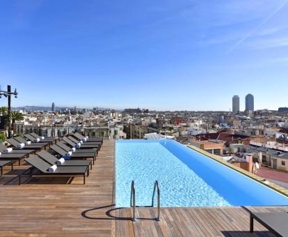 Foto de la piscina de borde infinito con impresionantes vistas a la ciudad y terraza con tumbonas.