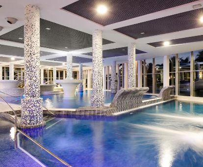 Amplia piscina cubierta con elementos de hidroterapia del centro de bienestar del hotel.