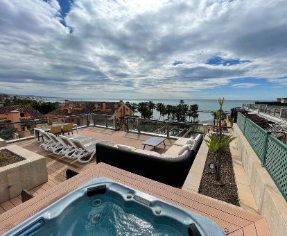 Fabulosa terraza con mobiliario, vistas al mar y un gran jacuzzi privado al aire libre del ático deluxe marina del hotel.