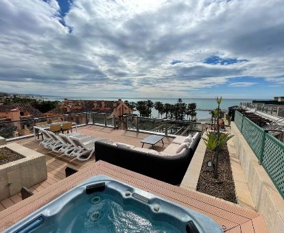 Fabulosa terraza con mobiliario, vistas al mar y un gran jacuzzi privado al aire libre del ático deluxe marina del hotel.