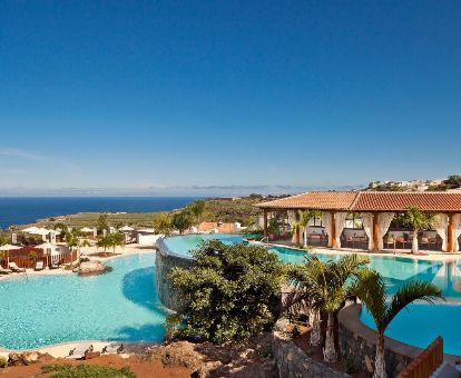 Exteriores con piscinas y vegetación de este hotel romántico junto al mar.