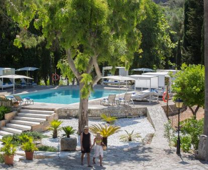 Hermosa zona exterior con piscina, solarium con tumbonas y vegetación de este hotel romántico.